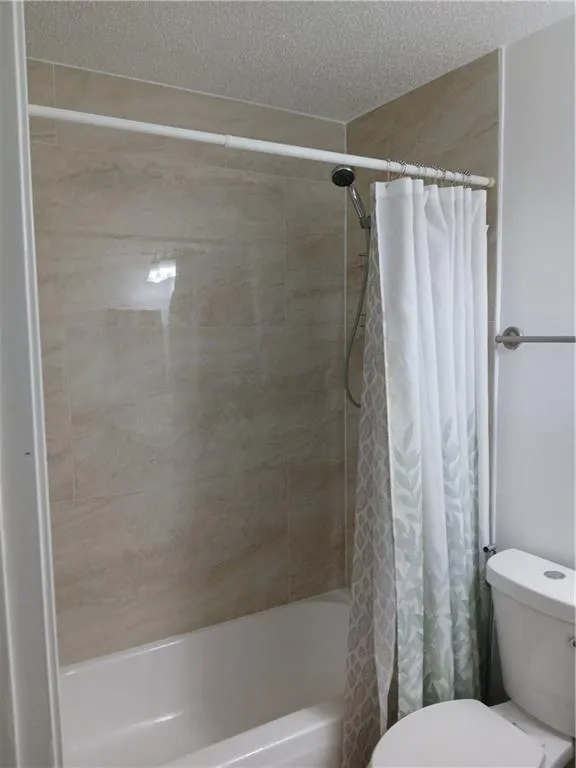 Bathroom featuring shower / bath combo with shower curtain and a textured ceiling