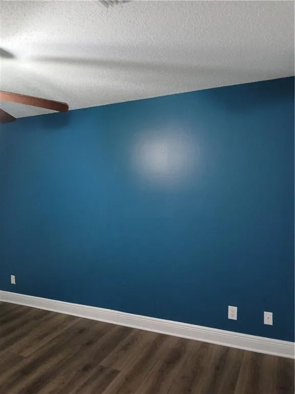 Empty room featuring dark wood-style floors and a textured ceiling
