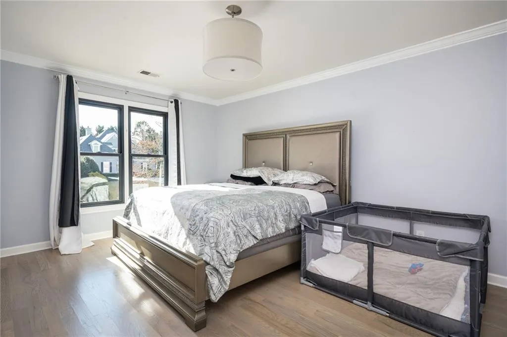 Bedroom featuring ornamental molding and hardwood / wood-style flooring