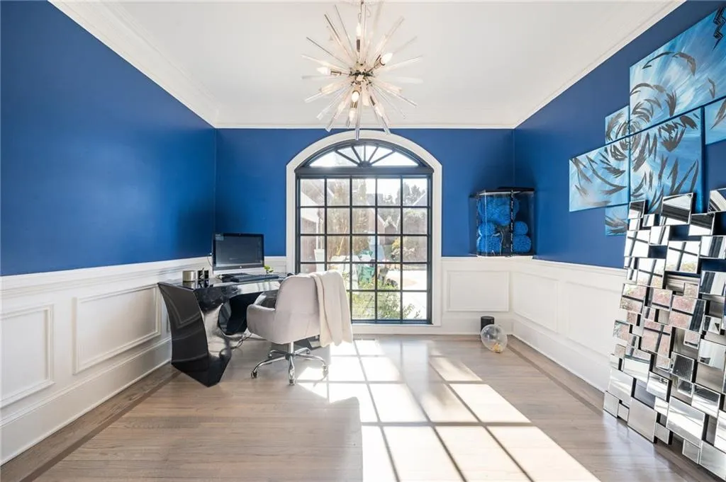 Office featuring a notable chandelier, ornamental molding, and light hardwood / wood-style flooring