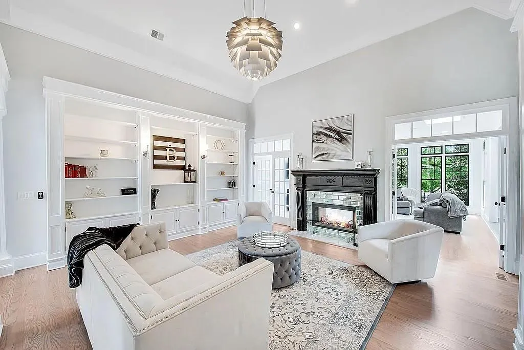 Living area with light wood-type flooring, high vaulted ceiling, visible vents, built in features, and a multi sided fireplace