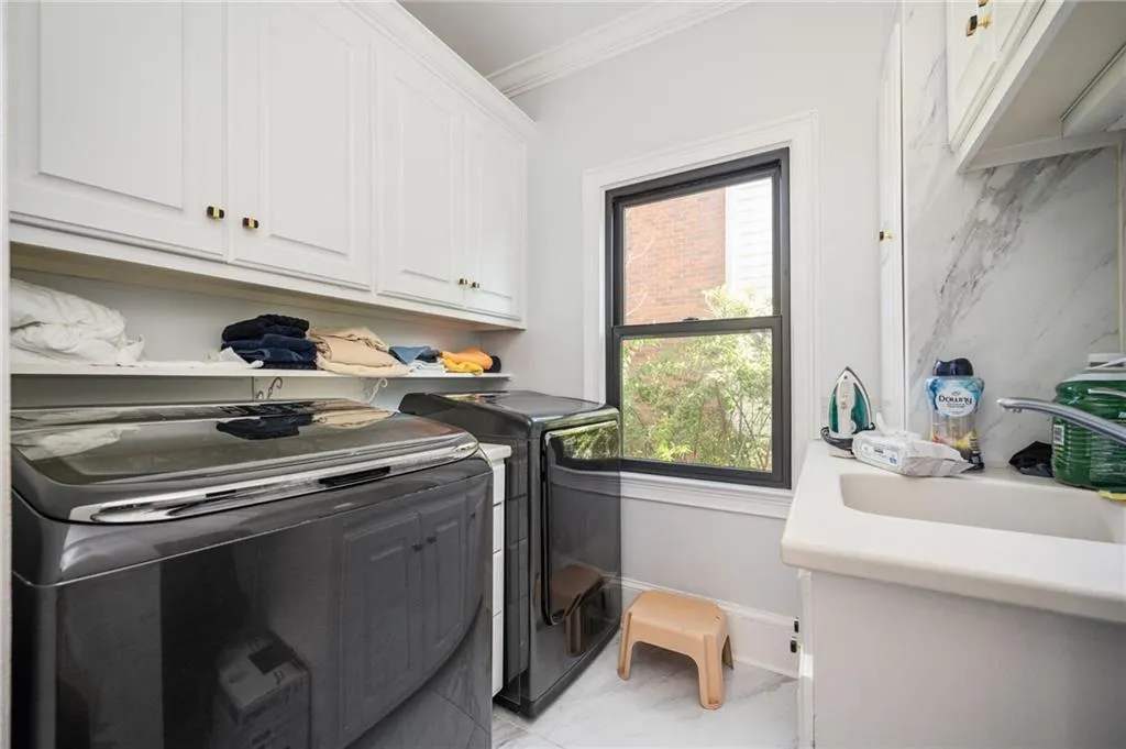 Laundry room featuring washer and clothes dryer, cabinets, ornamental molding, and sink