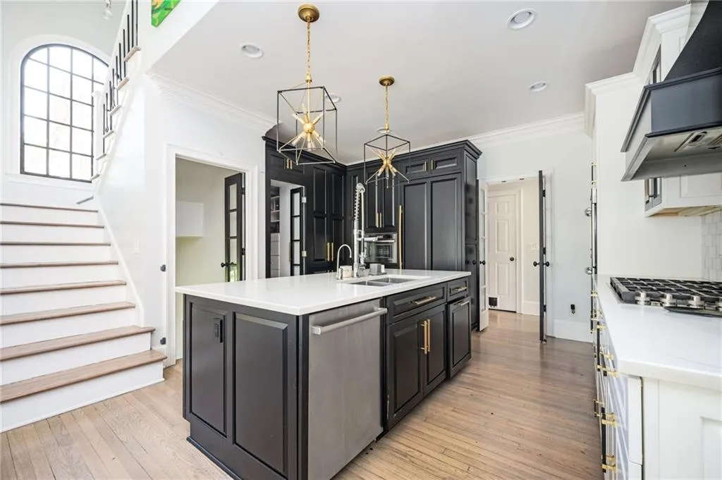 Kitchen featuring a kitchen island with sink, hanging light fixtures, light hardwood / wood-style flooring, appliances with stainless steel finishes, and custom range hood