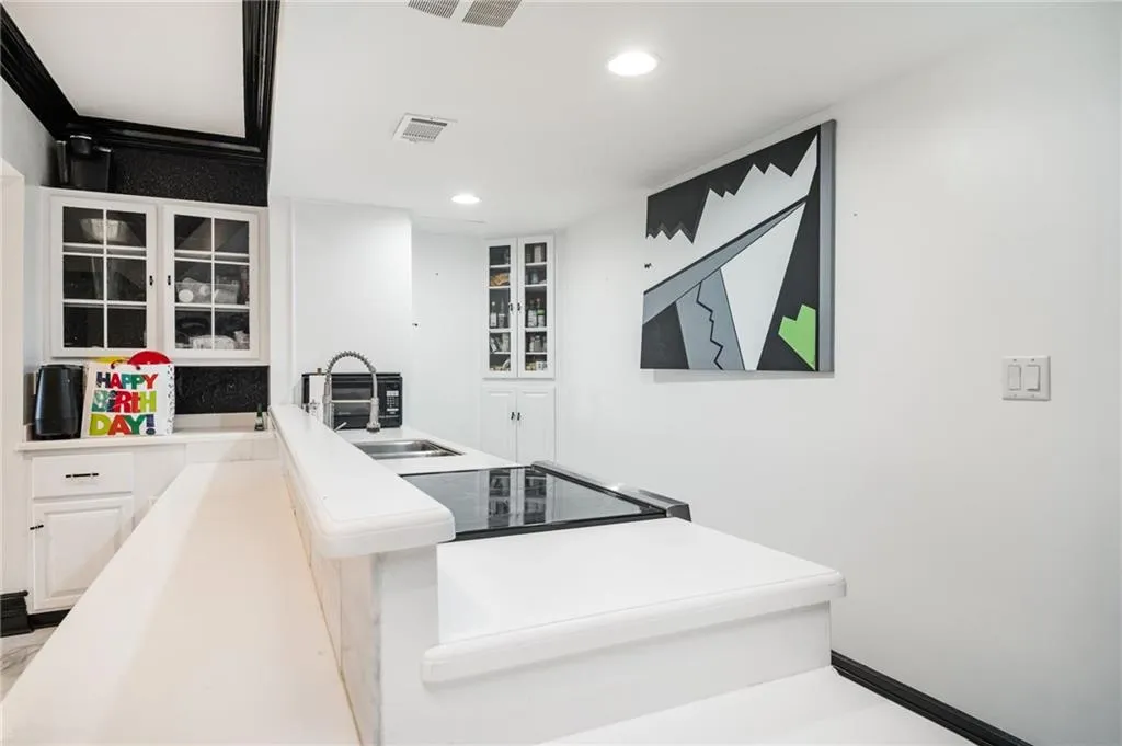 Kitchen featuring black range, white cabinetry, and sink