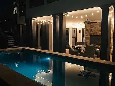 View of pool featuring a stone fireplace and ceiling fan