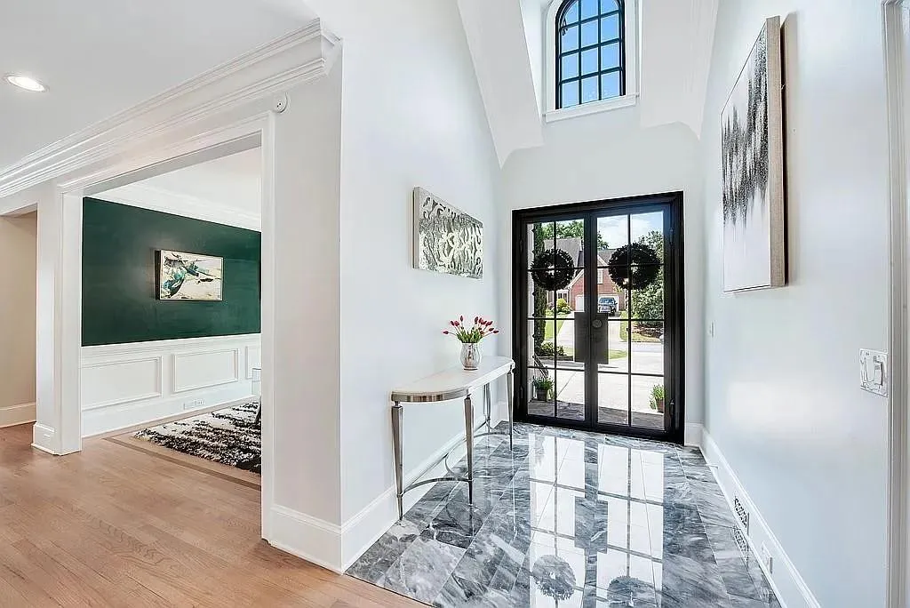 Foyer entrance with wood finished floors, wainscoting, a decorative wall, baseboards, and ornamental molding