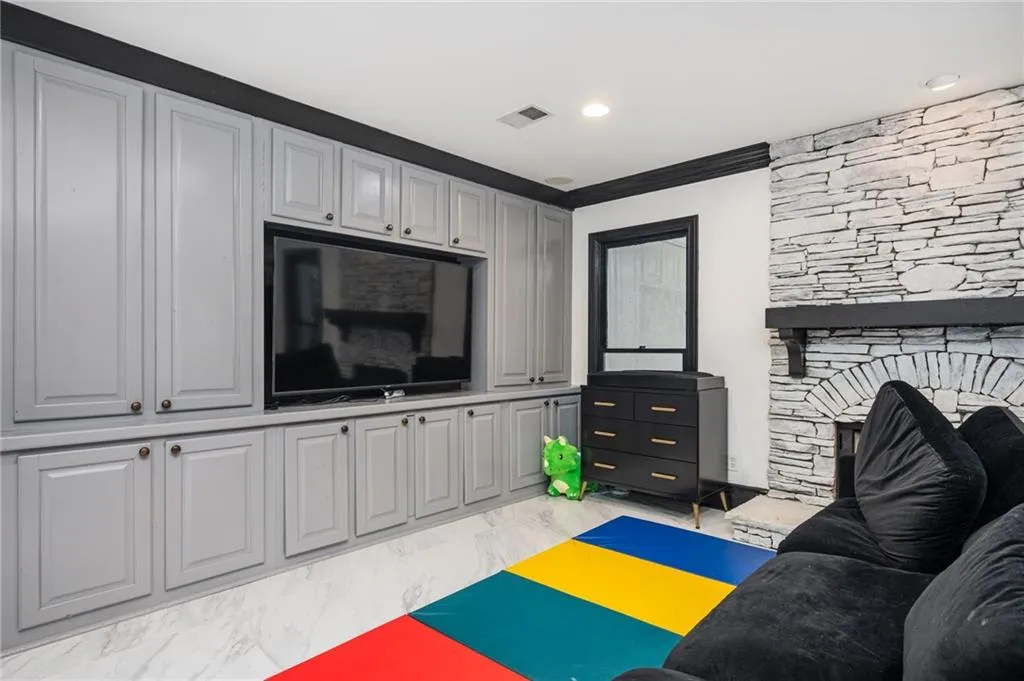 Living room with a stone fireplace and ornamental molding