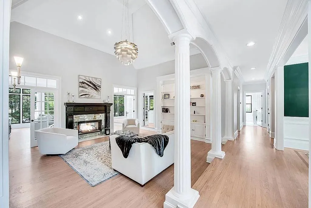 Living area with crown molding, recessed lighting, decorative columns, light wood finished floors, and a multi sided fireplace