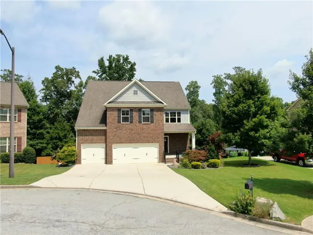 Brick and siding exterior featuring a covered front entry and a 3-car garage