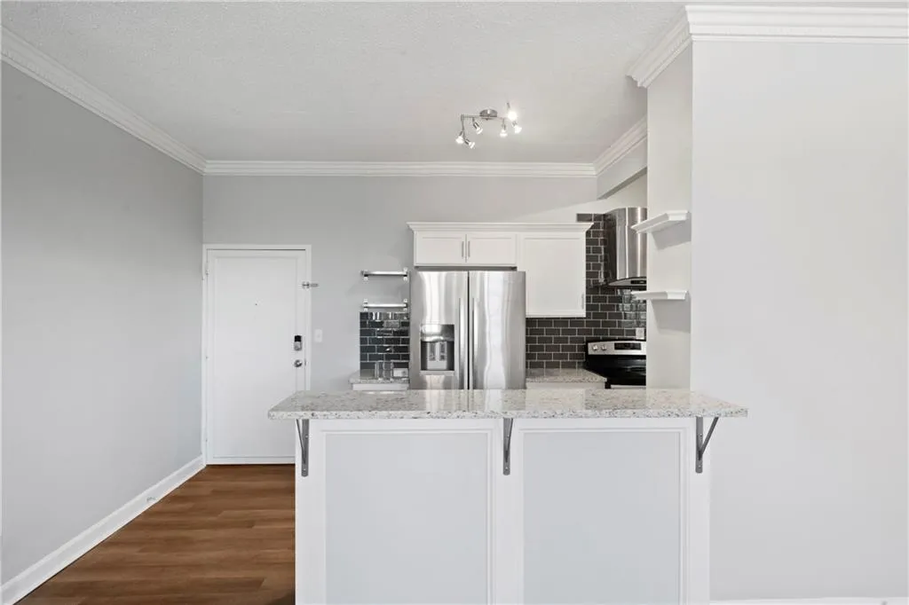 Kitchen featuring kitchen peninsula, white cabinetry, appliances with stainless steel finishes, a kitchen breakfast bar, and dark hardwood / wood-style flooring