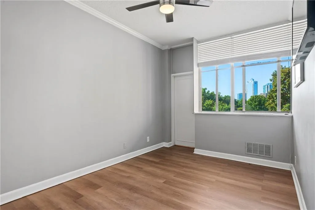 Empty room featuring ceiling fan, hardwood / wood-style floors, and crown molding