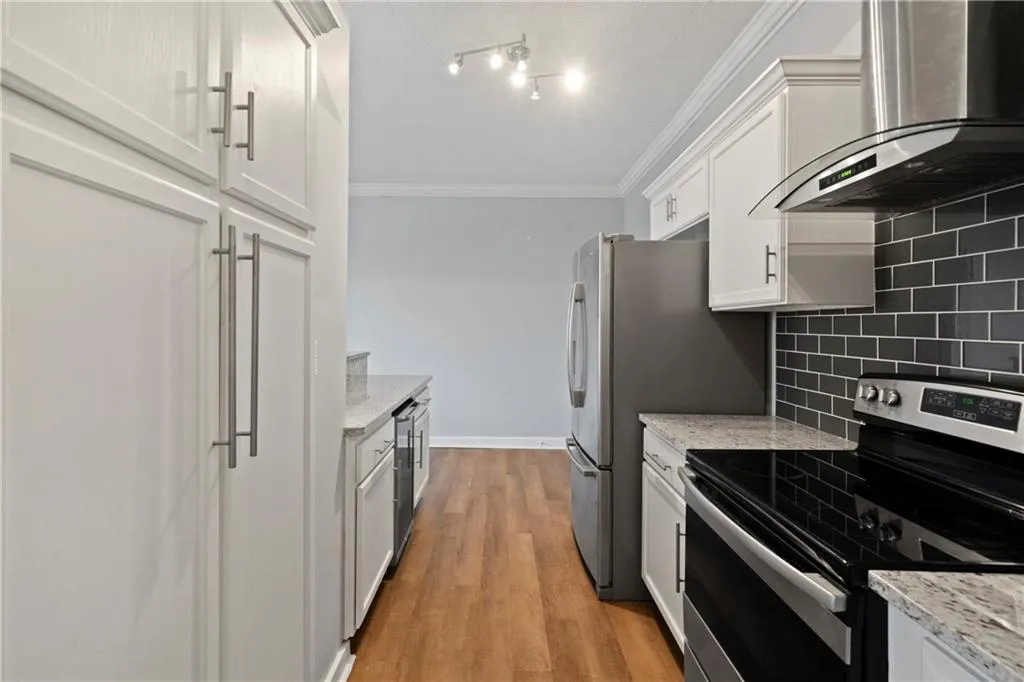 Kitchen featuring tasteful backsplash, light hardwood / wood-style flooring, wall chimney exhaust hood, white cabinetry, and electric stove