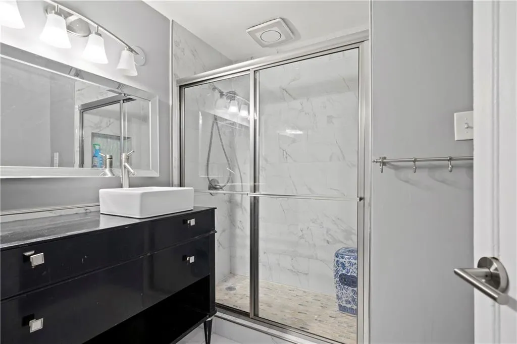 Bathroom featuring a shower with shower door and vanity
