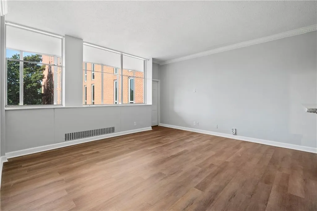 Empty room with a textured ceiling, hardwood / wood-style flooring, and crown molding