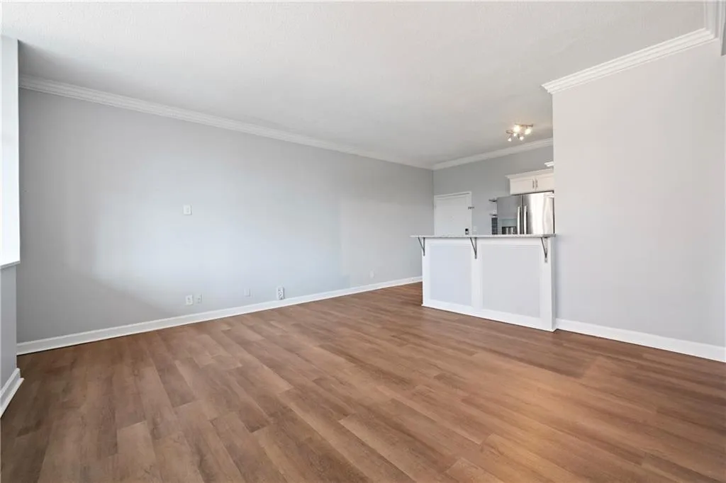 Unfurnished living room with ornamental molding and hardwood / wood-style floors