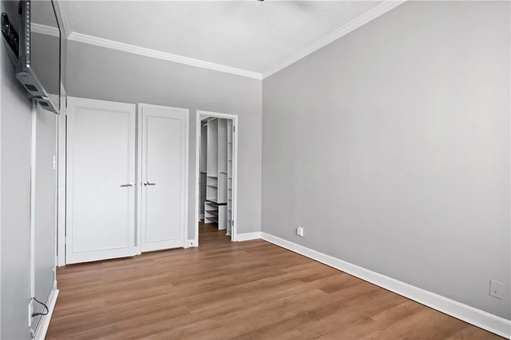 Unfurnished bedroom featuring a textured ceiling, ornamental molding, and light hardwood / wood-style flooring