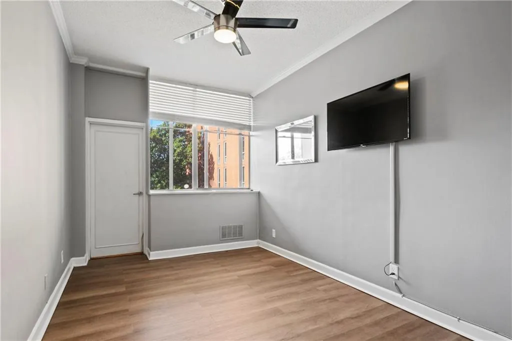 Empty room featuring a textured ceiling, light hardwood / wood-style floors, ornamental molding, and ceiling fan