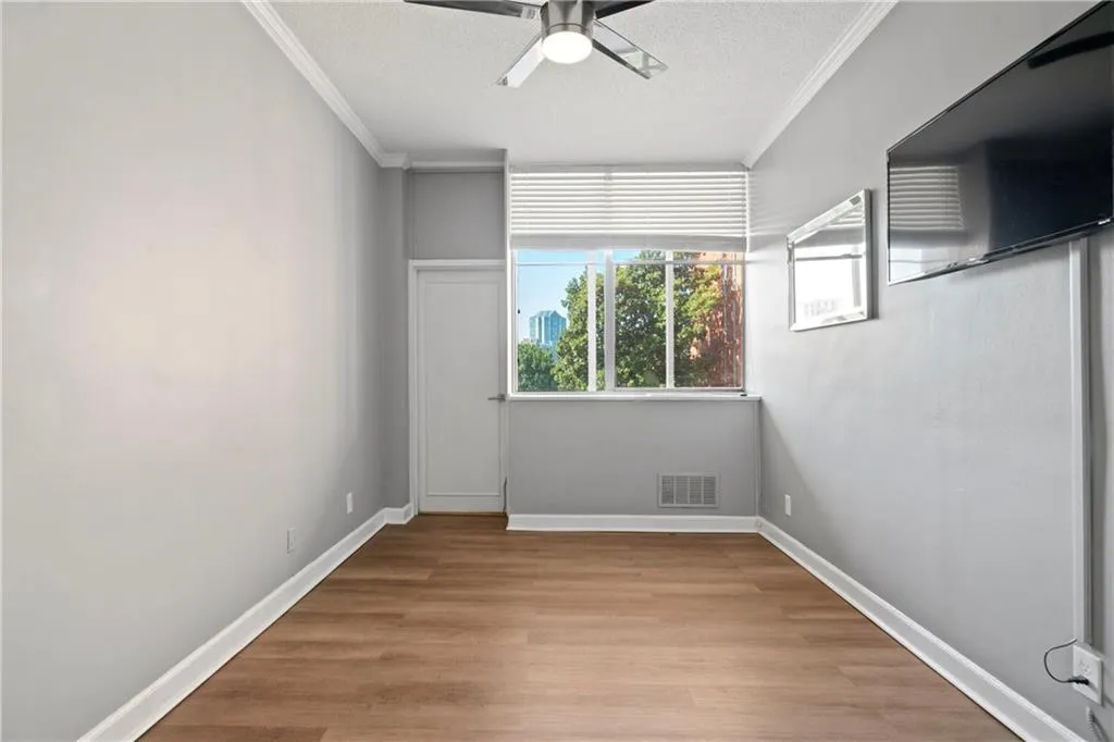 Unfurnished room with ornamental molding, light wood-type flooring, ceiling fan, and a textured ceiling