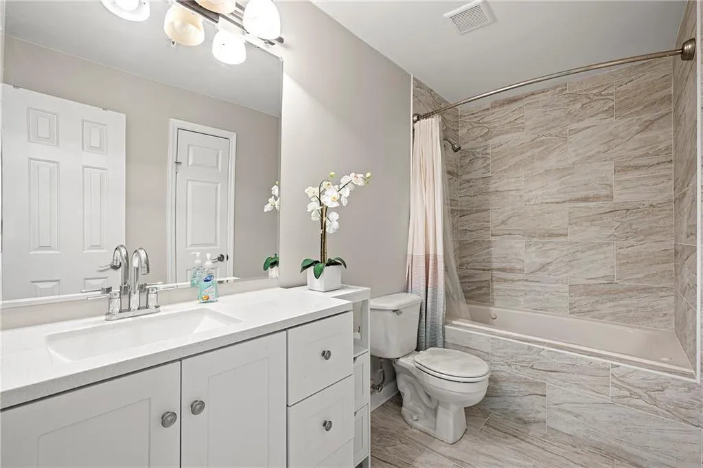 Bathroom featuring a white vanity with an integrated sink, chrome faucet, and overhead light fixture