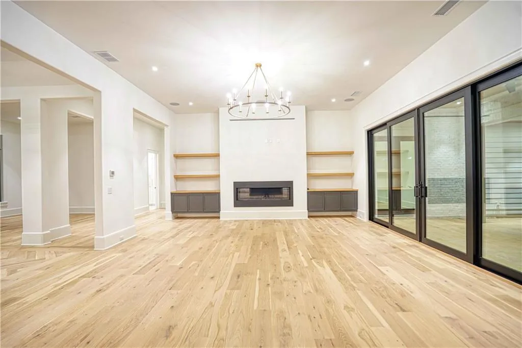 Unfurnished living room with an inviting chandelier, plenty of natural light, and light hardwood / wood-style flooring