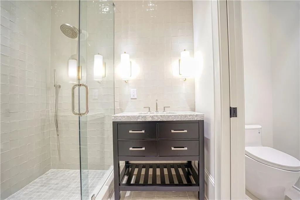 Bathroom with vanity, toilet, an enclosed shower, backsplash, and tile patterned flooring