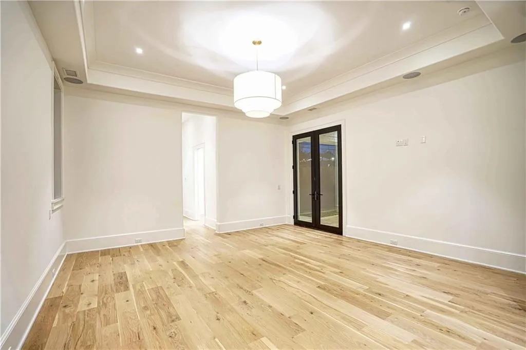 Empty room with french doors, a tray ceiling, and light wood-type flooring