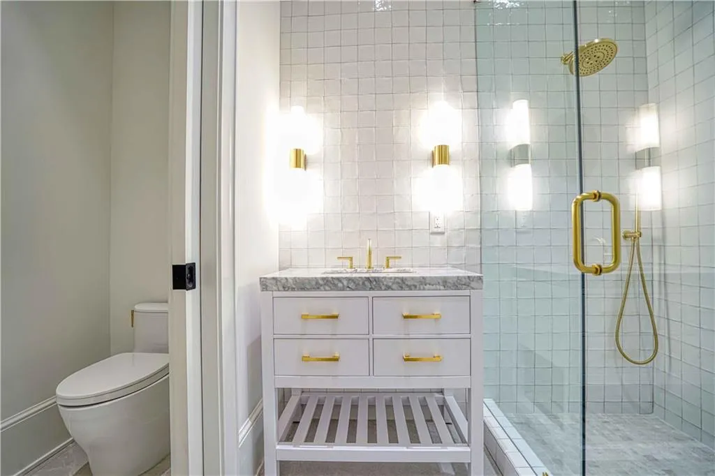 Bathroom featuring vanity, a shower with shower door, and toilet