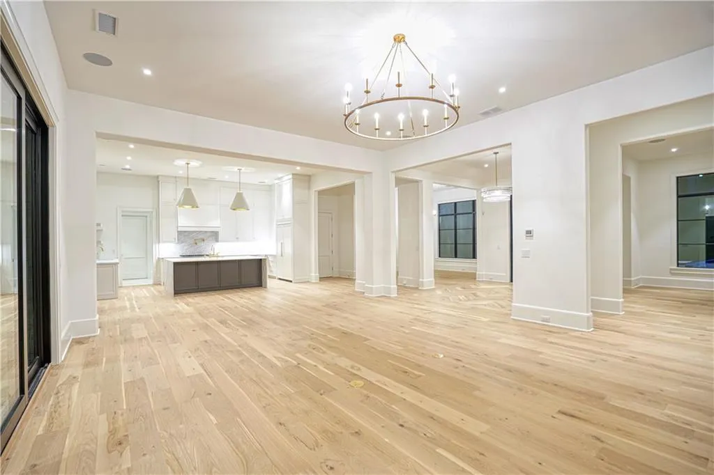 Unfurnished living room featuring light wood-type flooring and a notable chandelier