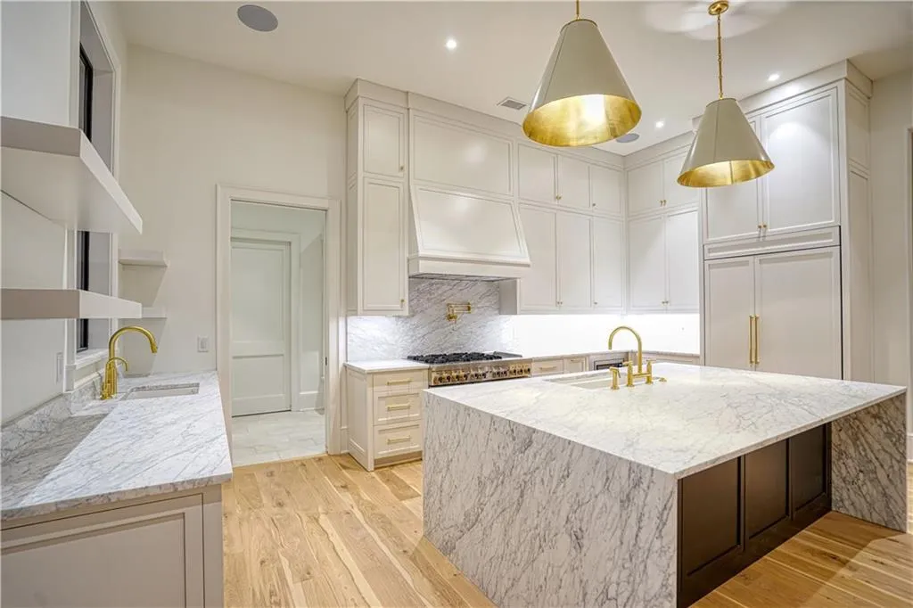 Kitchen with light stone countertops, an island with sink, light hardwood / wood-style flooring, and sink