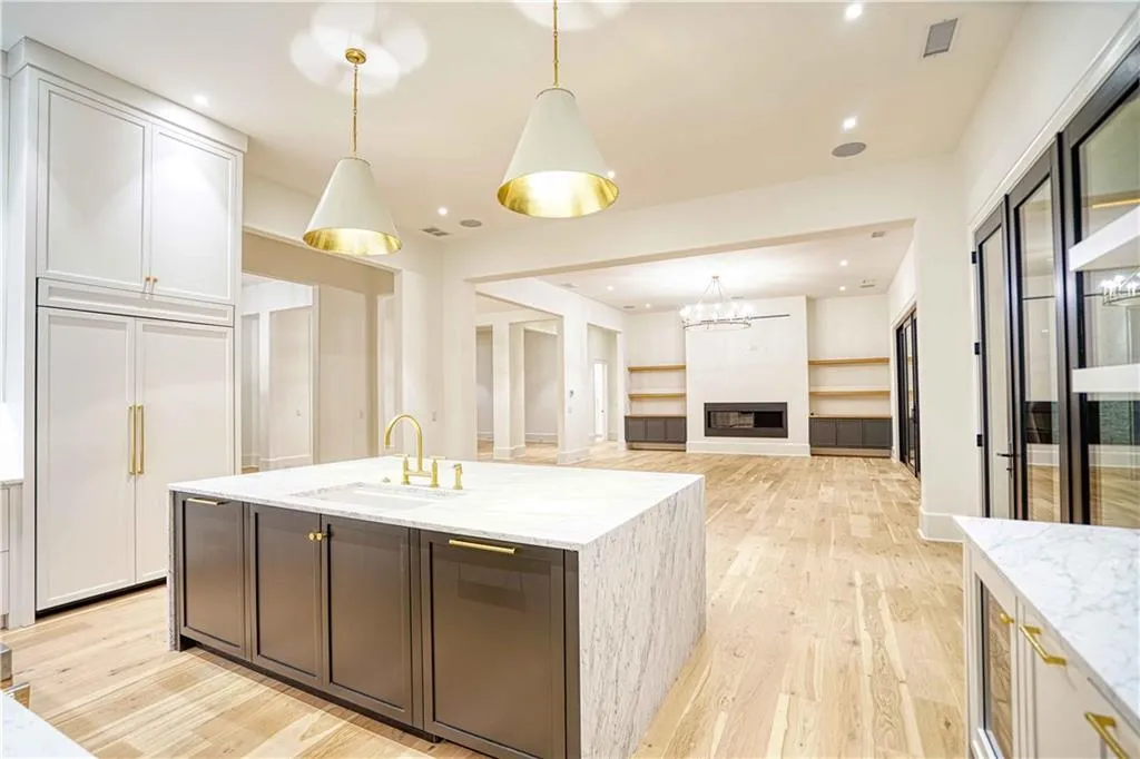 Kitchen featuring light stone counters, hanging light fixtures, sink, a fireplace, and light wood-type flooring