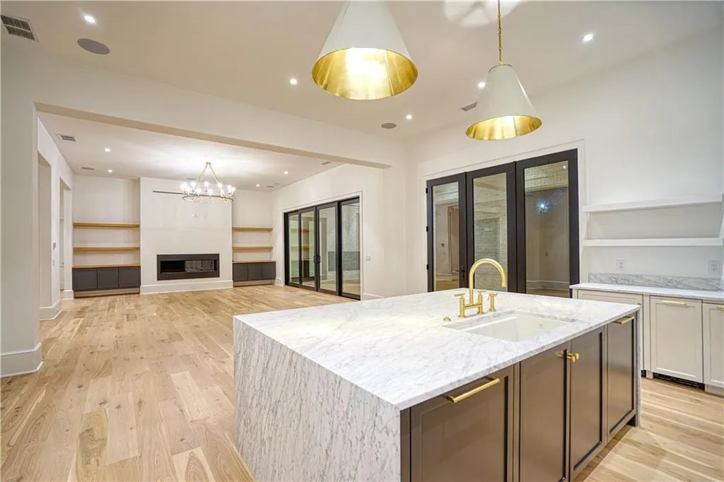 Kitchen featuring light hardwood / wood-style flooring, decorative light fixtures, light stone countertops, and sink