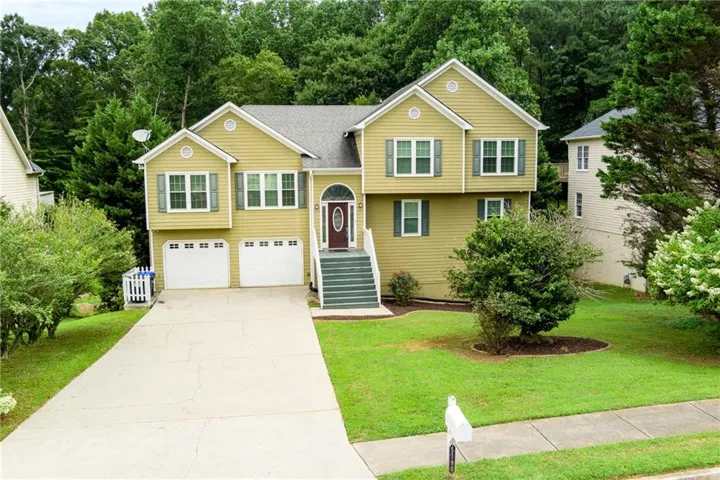 Split-level residence featuring a Mustard siding exterior, dark green shutters, and a prominent arched entryway