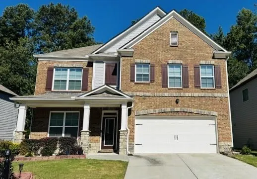 Brick exterior with shuttered windows, a two-car garage, and a covered porch with stone-clad columns