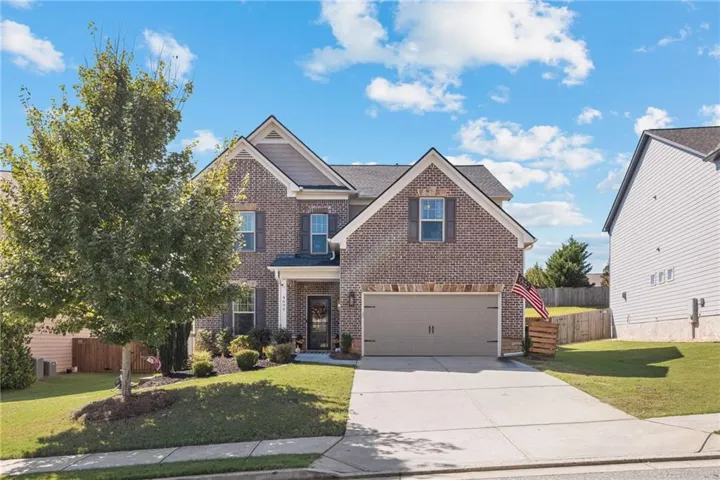 Brick and siding exterior with multiple gables, an attached garage, a paved driveway, and a covered entry