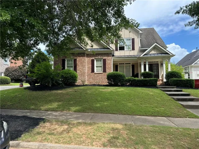 Two-story residence featuring a brick and siding exterior, a covered front porch with white columns, and a dark front door