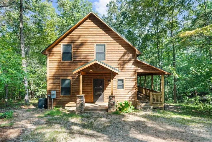 Wood-sided exterior featuring a covered front porch with stone-clad columns and a covered side porch with a ramp