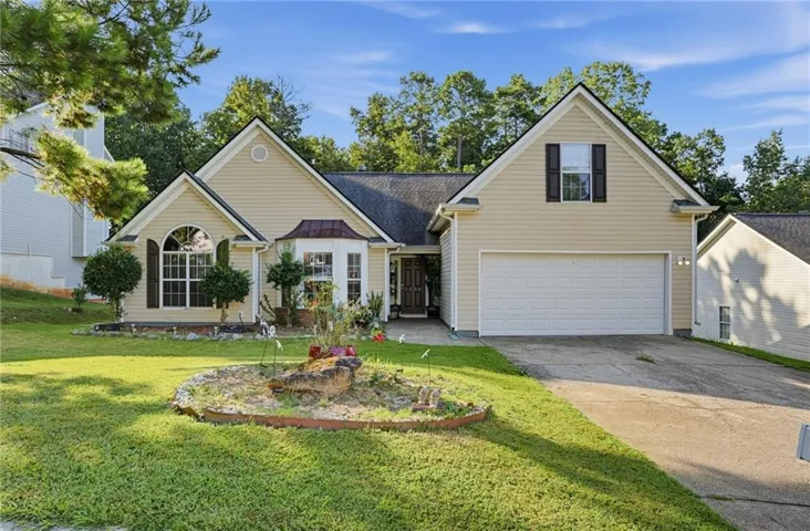 Traditional-style exterior with light-colored siding, a prominent two-car garage, and a peaked roofline