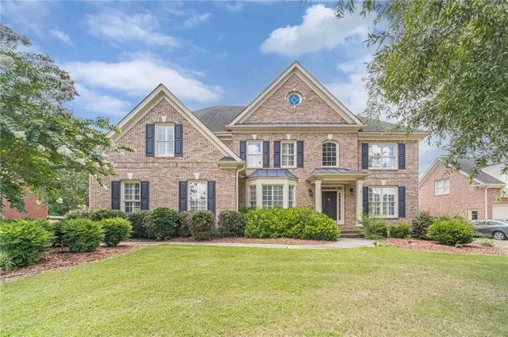 Brick facade residence featuring a prominent bay window, gabled rooflines, and a well-maintained front lawn