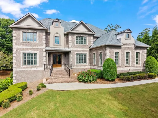 Brick exterior with stone accents, multiple dormer windows, a covered entry, and a prominent front portico