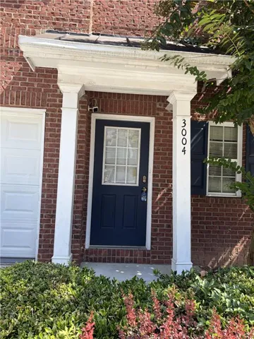 Brick facade with a covered entry featuring white columns and a dark-paneled door with a grid-patterned window