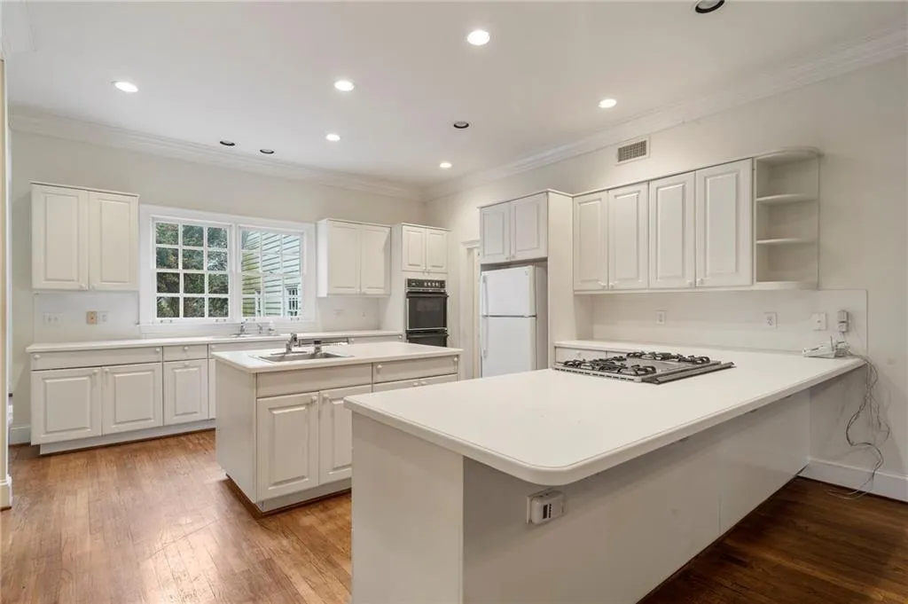 Kitchen featuring open shelves, white cabinets, light countertops, freestanding refrigerator, and a peninsula