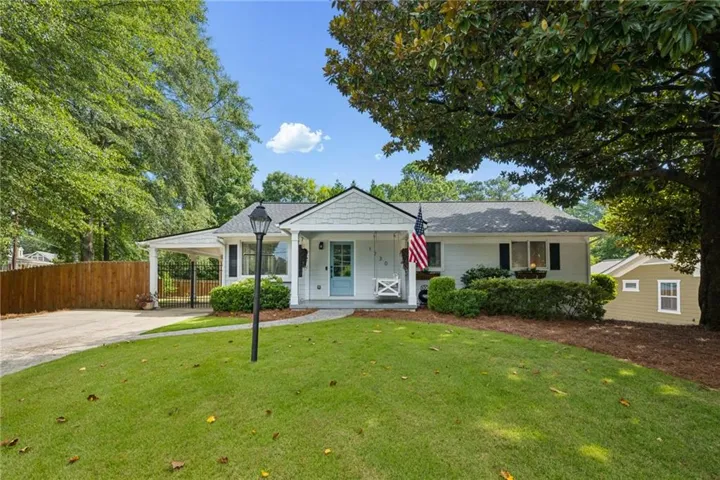 Single-story residence featuring a covered carport, light blue entry door, and a front patio with a swing bench