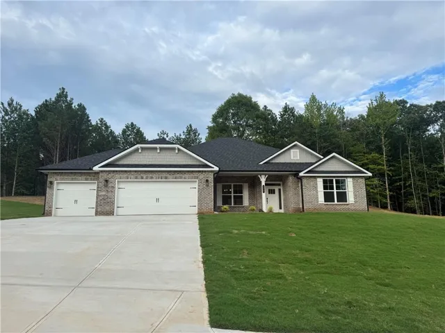 Contemporary ranch-style residence featuring a brick facade, gabled rooflines, a 3-car garage, concrete driveway and landscaped yard.