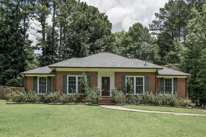 Brick exterior featuring a gray shingle roof and green shutters
