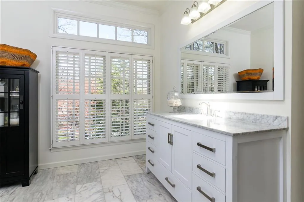Primary Bathroom with double vanity, Marble tile and Countertops and Skylight above