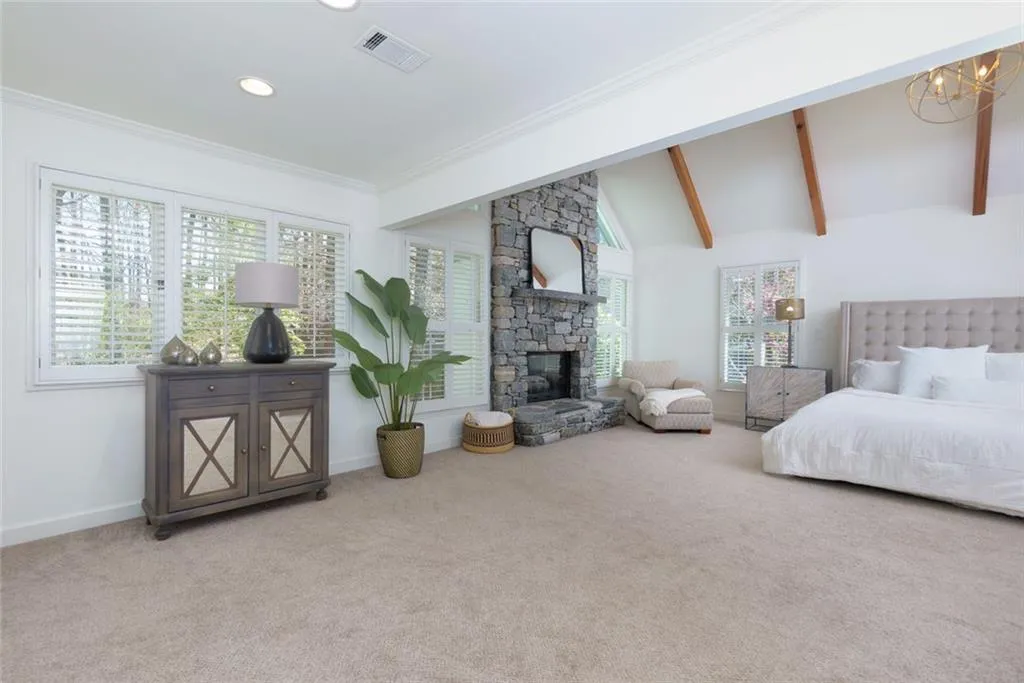Primary Bedroom with Seating Area, Stone Fireplace and Beamed Ceilings