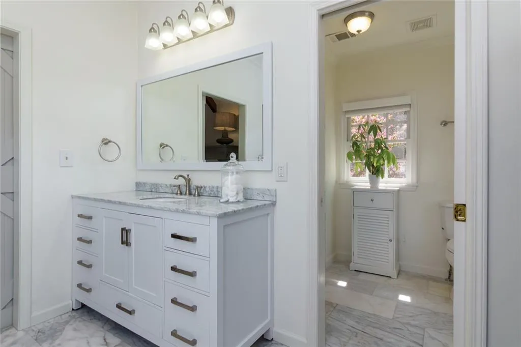 Primary Bathroom with double vanity, Marble tile and Countertops and Skylight above