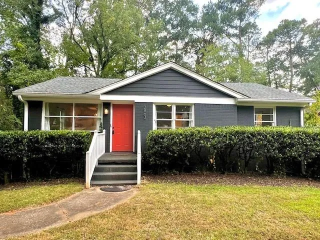 Charcoal exterior with an accent front door, white painted porch railings, and a concrete walkway