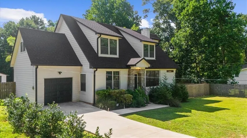 Contemporary home exterior featuring white siding, a dark shingle roof, stone accents, and a two-car garage