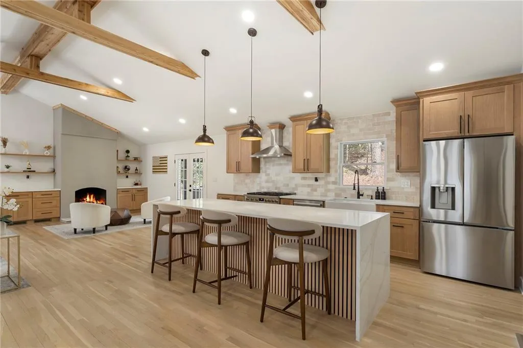 Kitchen with a breakfast bar, stainless steel appliances, a center island, backsplash, and light wood finished floors
